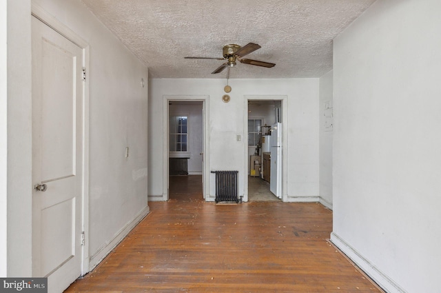 spare room featuring a textured ceiling, radiator heating unit, dark hardwood / wood-style floors, and ceiling fan