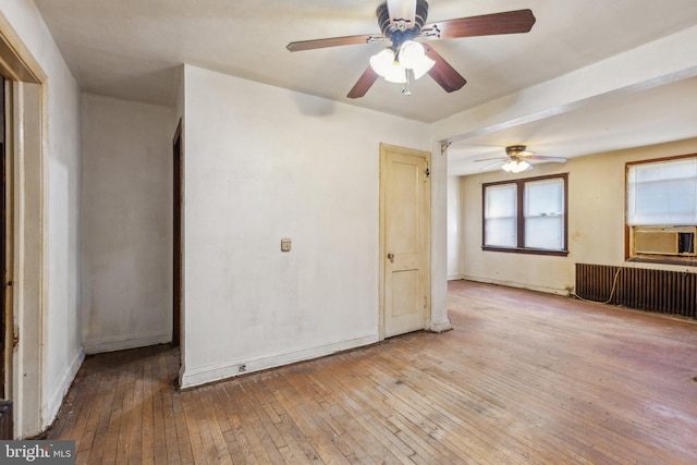 spare room featuring light hardwood / wood-style floors, cooling unit, radiator heating unit, and ceiling fan