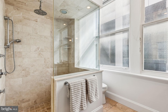 bathroom featuring a tile shower, tile patterned floors, a healthy amount of sunlight, and toilet