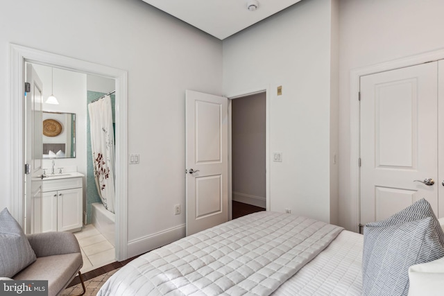 bedroom with connected bathroom, tile patterned flooring, and sink