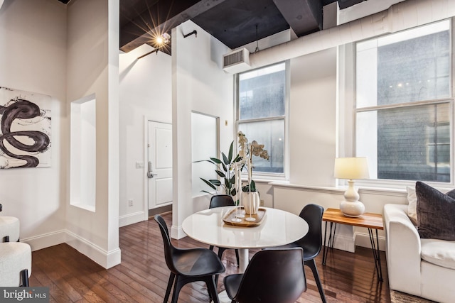 dining space with beam ceiling, dark hardwood / wood-style flooring, and a high ceiling