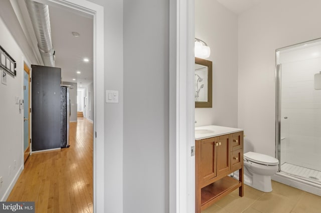 bathroom featuring vanity, toilet, a shower with shower door, and hardwood / wood-style floors