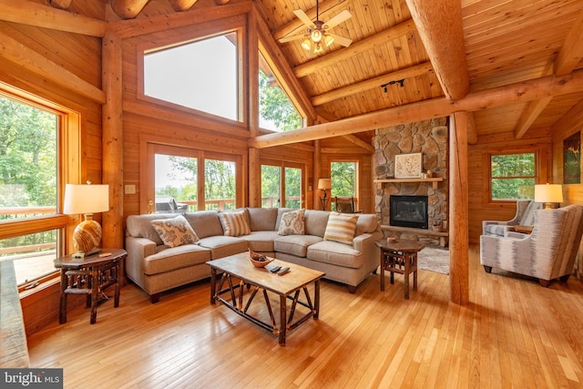 living room featuring a stone fireplace, high vaulted ceiling, light hardwood / wood-style flooring, and wood ceiling