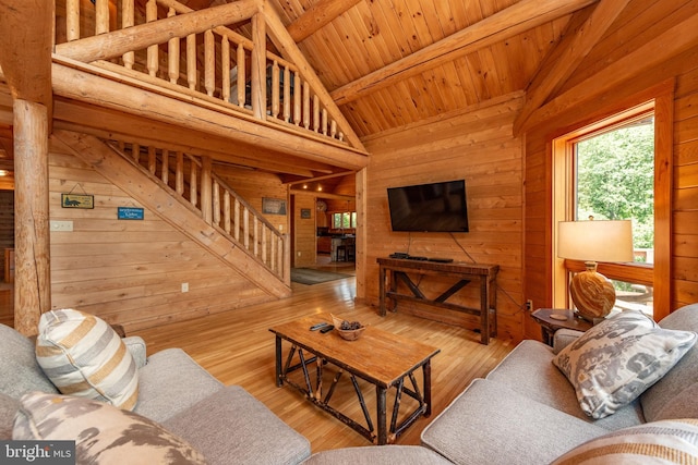 living room featuring high vaulted ceiling, wood walls, beamed ceiling, wooden ceiling, and light hardwood / wood-style flooring