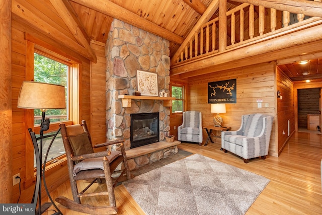 living room with wooden ceiling, hardwood / wood-style flooring, a stone fireplace, and high vaulted ceiling