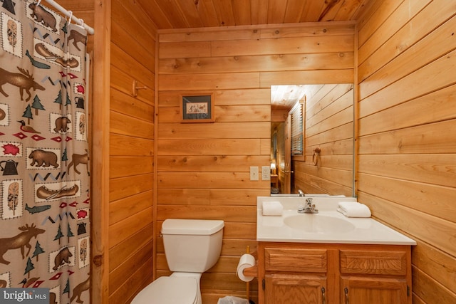 bathroom with toilet, vanity, wooden walls, and wooden ceiling