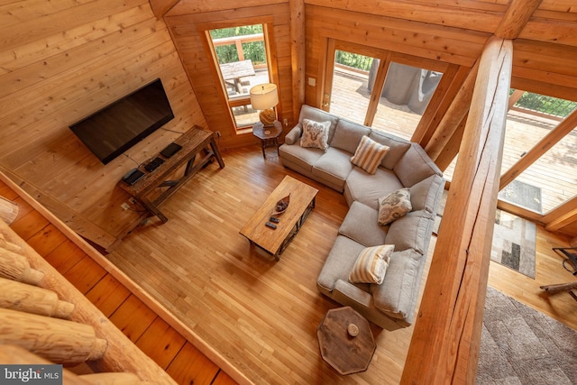 living room with hardwood / wood-style floors, wooden walls, and vaulted ceiling with skylight