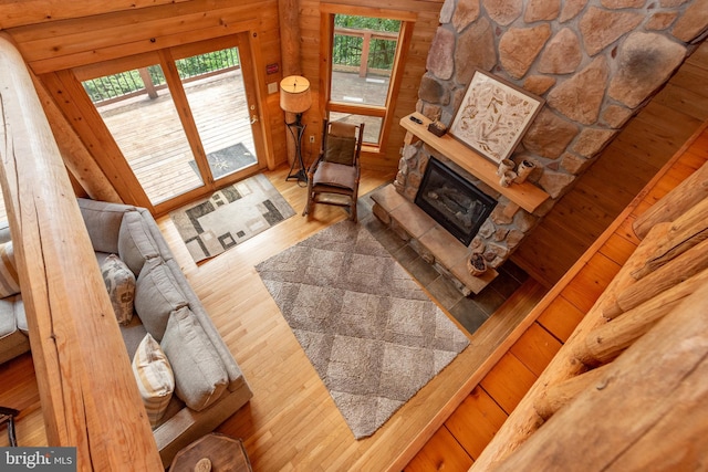 living room featuring a stone fireplace, a wealth of natural light, and wood-type flooring