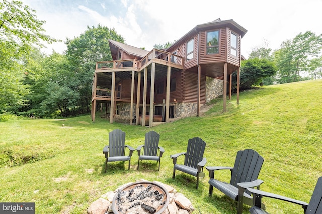 back of property featuring a lawn, an outdoor fire pit, and a wooden deck