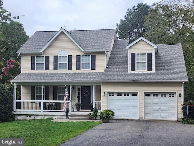 view of front of home featuring covered porch, a garage, and a front yard