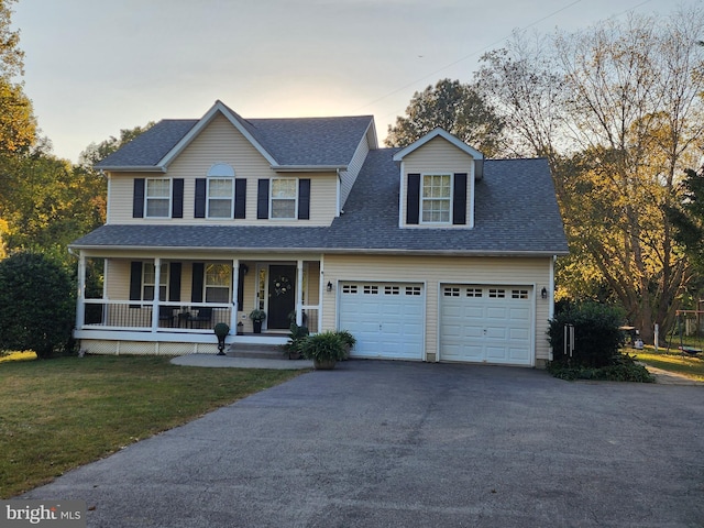 view of front of property featuring covered porch, a garage, and a lawn