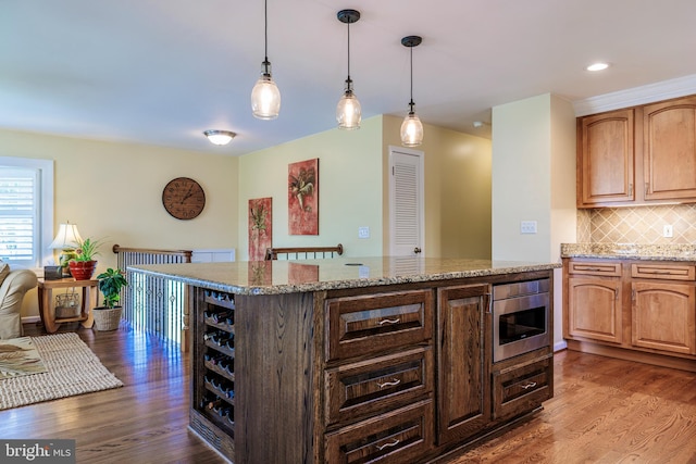 kitchen featuring pendant lighting, dark hardwood / wood-style floors, tasteful backsplash, and light stone counters