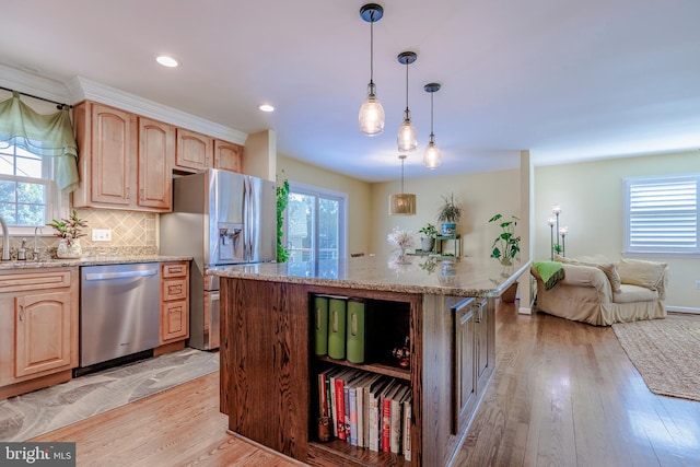 kitchen featuring stainless steel appliances, light stone countertops, light wood-type flooring, and a healthy amount of sunlight