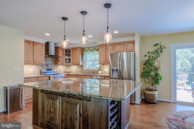 kitchen with a kitchen island, light stone counters, light wood-type flooring, wall chimney range hood, and appliances with stainless steel finishes