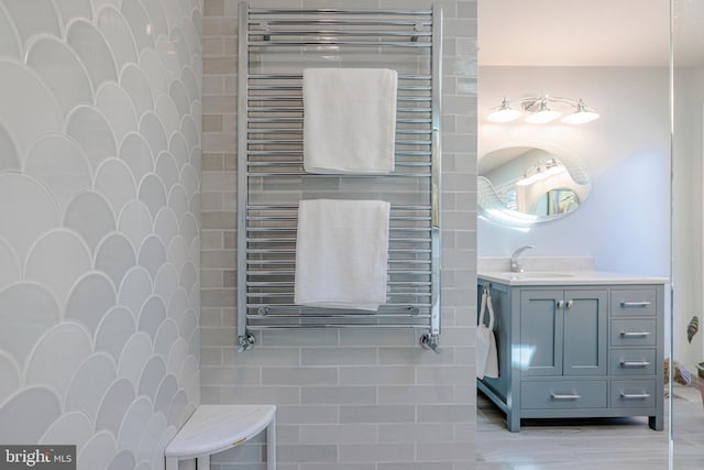 bathroom with wood-type flooring, radiator, vanity, and tile walls