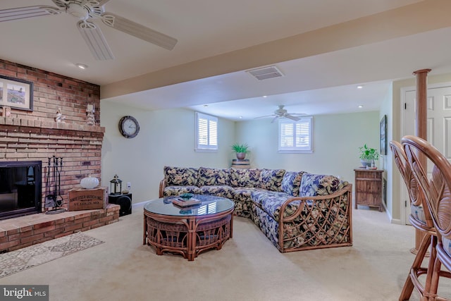 carpeted living room with a brick fireplace, ornate columns, and ceiling fan