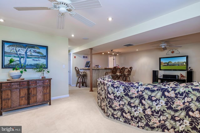 living room with light carpet, bar, and ceiling fan