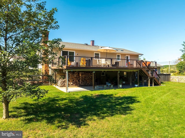 rear view of house featuring a deck, a lawn, and a patio area