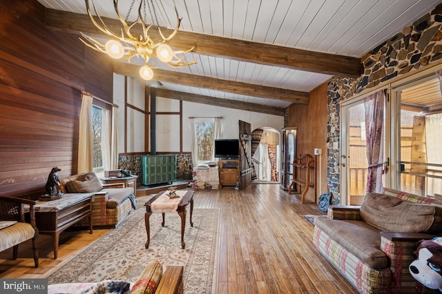 living room with wood walls, lofted ceiling with beams, wooden ceiling, an inviting chandelier, and wood-type flooring