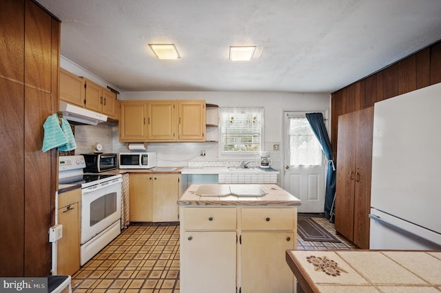 kitchen with decorative backsplash, white appliances, a textured ceiling, sink, and a center island