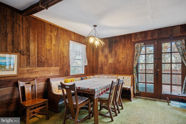 dining room with wood walls, carpet floors, and french doors