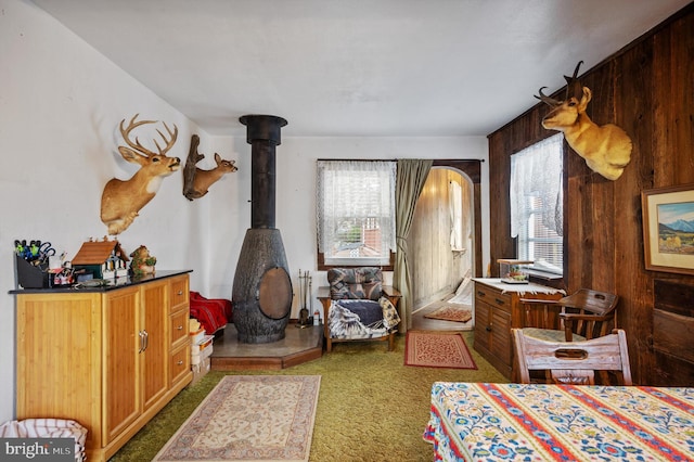 carpeted bedroom featuring a wood stove and wooden walls