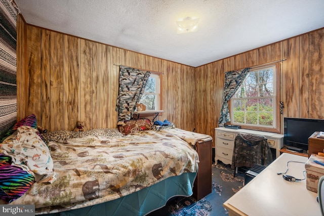 carpeted bedroom with a textured ceiling and wood walls