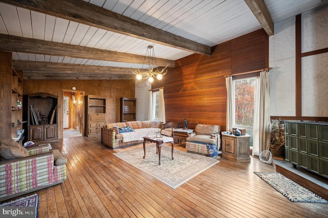 living room featuring wooden ceiling, an inviting chandelier, lofted ceiling with beams, wood walls, and hardwood / wood-style floors