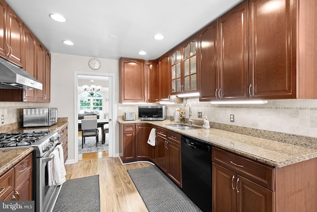 kitchen featuring light wood-type flooring, light stone countertops, a chandelier, and stainless steel appliances