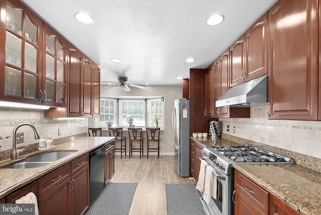 kitchen featuring ceiling fan, sink, light hardwood / wood-style flooring, stainless steel appliances, and light stone countertops