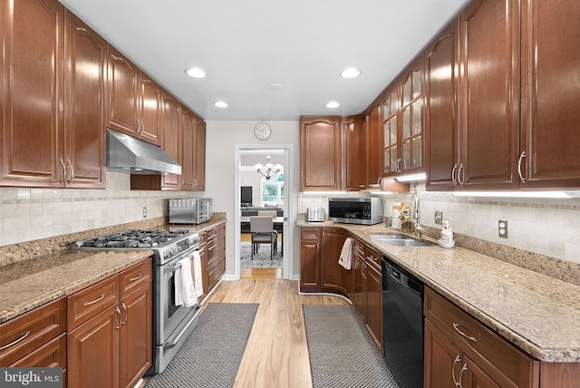 kitchen featuring light stone counters, stainless steel appliances, sink, light hardwood / wood-style floors, and a chandelier