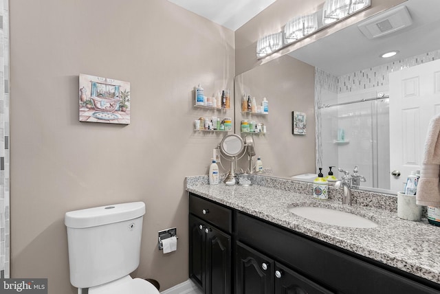 bathroom featuring vanity, toilet, and a shower with door