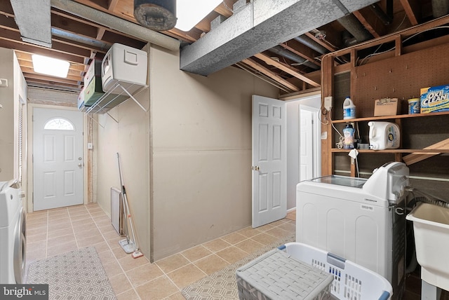 clothes washing area with separate washer and dryer, sink, and light tile patterned floors