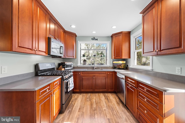 kitchen featuring appliances with stainless steel finishes, sink, and light hardwood / wood-style floors