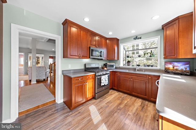 kitchen with appliances with stainless steel finishes, sink, and light wood-type flooring