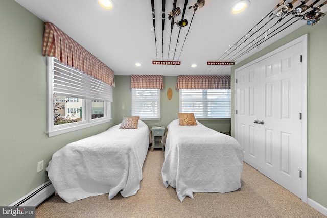 carpeted bedroom with a baseboard heating unit, multiple windows, and a closet