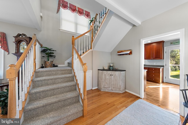 stairway with hardwood / wood-style flooring and lofted ceiling with beams