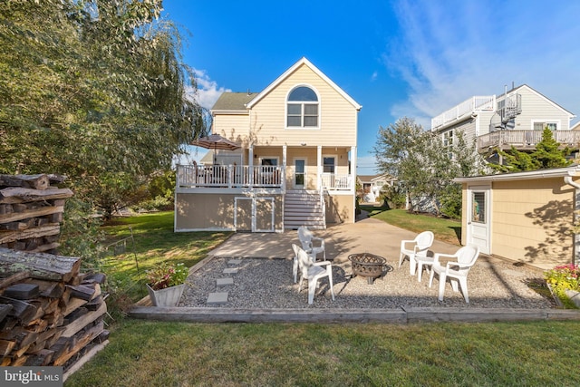 rear view of property featuring a yard, a patio area, a deck, and a fire pit