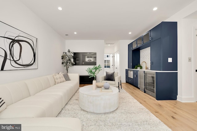 living room with wine cooler, light wood-type flooring, and bar area