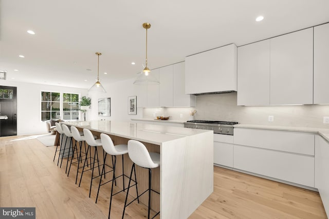 kitchen with a spacious island, light hardwood / wood-style flooring, hanging light fixtures, and white cabinetry