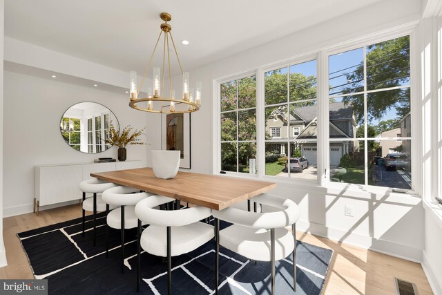 dining area with radiator heating unit, a notable chandelier, and light wood-type flooring