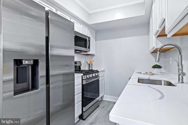 kitchen with light stone counters, sink, light hardwood / wood-style flooring, white cabinetry, and appliances with stainless steel finishes