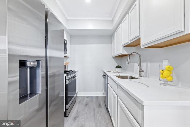 kitchen featuring light hardwood / wood-style floors, sink, light stone countertops, appliances with stainless steel finishes, and white cabinetry