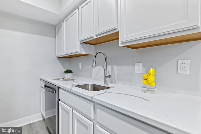 kitchen with light stone countertops, white cabinets, sink, and stainless steel dishwasher