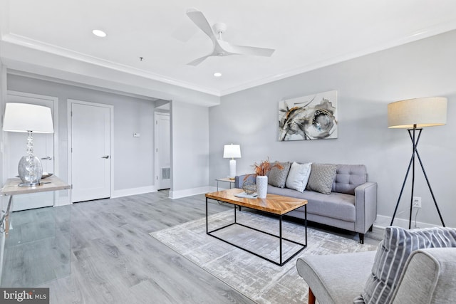 living room featuring ornamental molding, light wood-type flooring, and ceiling fan