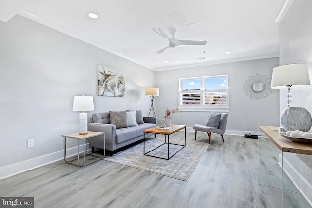 living room featuring crown molding, light wood-type flooring, and ceiling fan