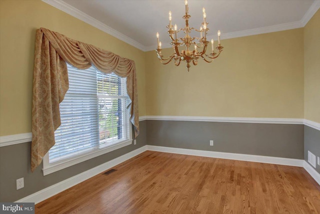 empty room featuring ornamental molding, hardwood / wood-style flooring, and a chandelier