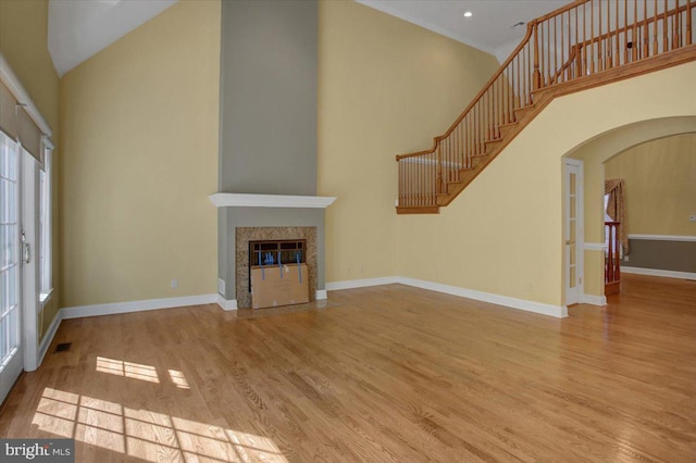 unfurnished living room with a towering ceiling and light hardwood / wood-style floors