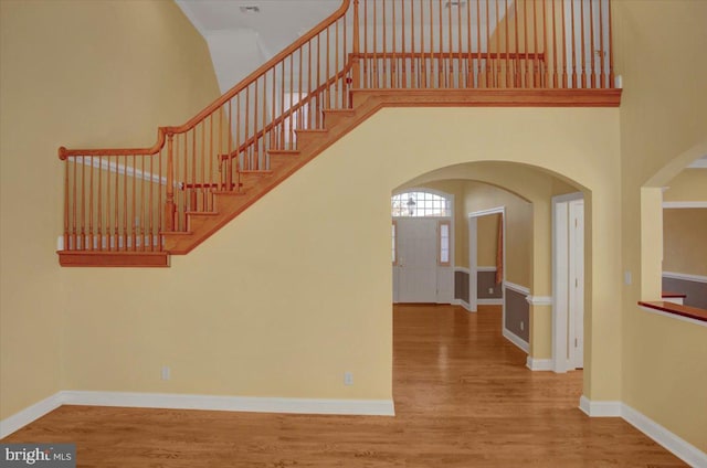 stairway with wood-type flooring and a high ceiling