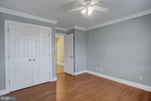 unfurnished bedroom with ornamental molding, wood-type flooring, a closet, and ceiling fan